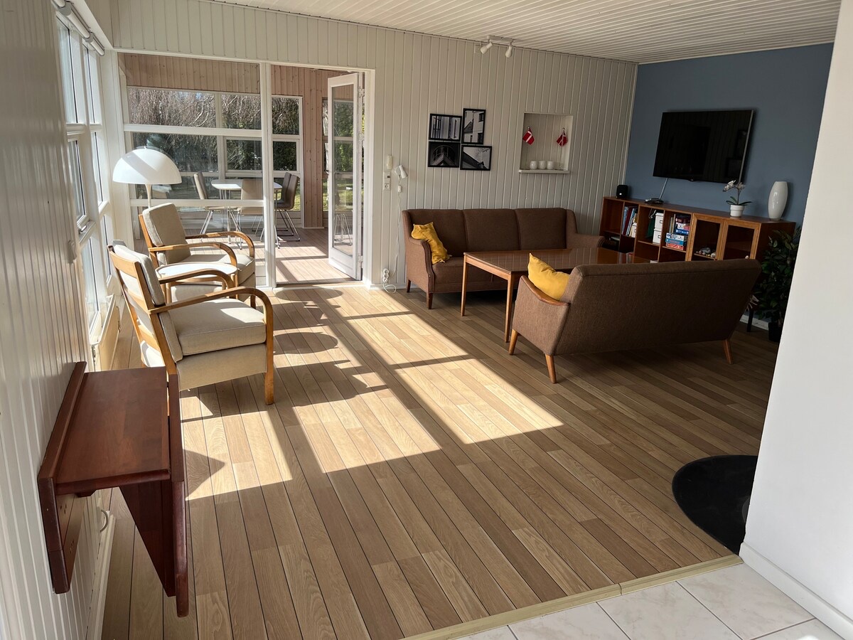 Lys stue med sofa og store vinduer